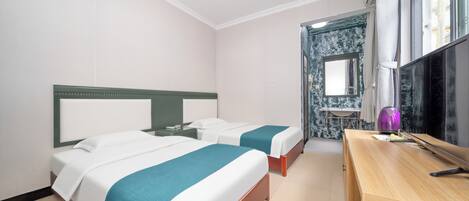 A hotel room with two beds, a wooden desk, a mirror, and a bathroom visible through an open door.