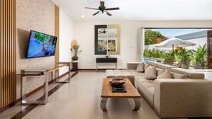 A modern living room with a flat-screen TV, a ceiling fan, a large window with an umbrella, and a sofa.