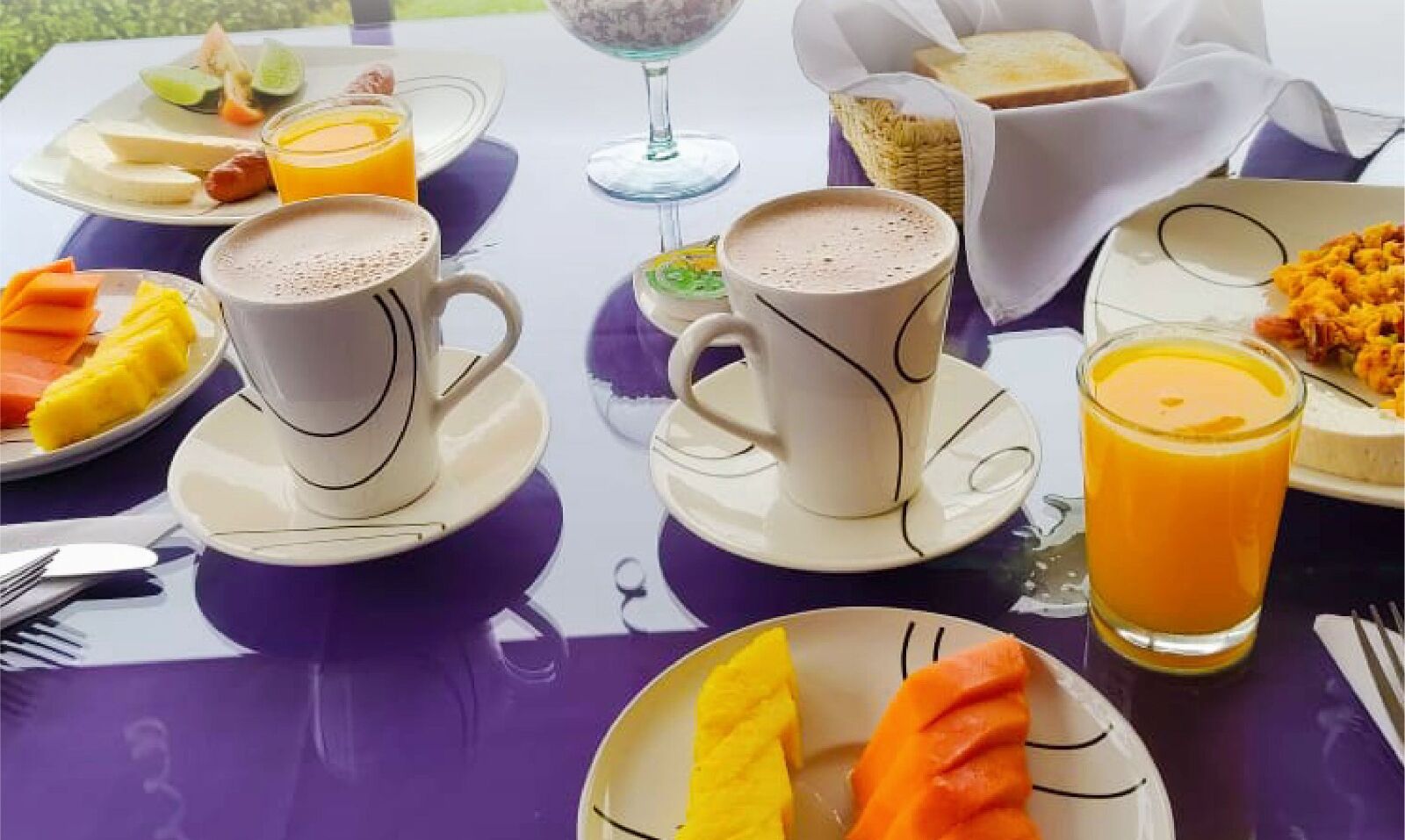 A table set with breakfast items including fruit, coffee, and juice.