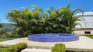 Un bain à remous entouré d’une végétation tropicale luxuriante, avec en toile de fond un ciel bleu azur.