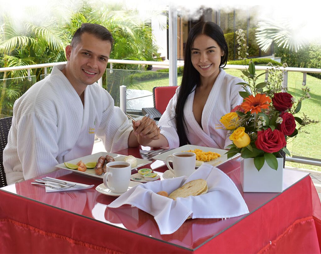 A dining table with breakfast items, a coffee cup, and a bouquet of flowers.