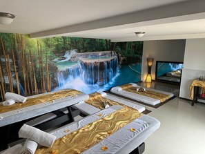 A spa room with massage tables, a large mural of a waterfall, and a television on a stand. - Hotel Jade Spa (Santa Rosa de Cabal)