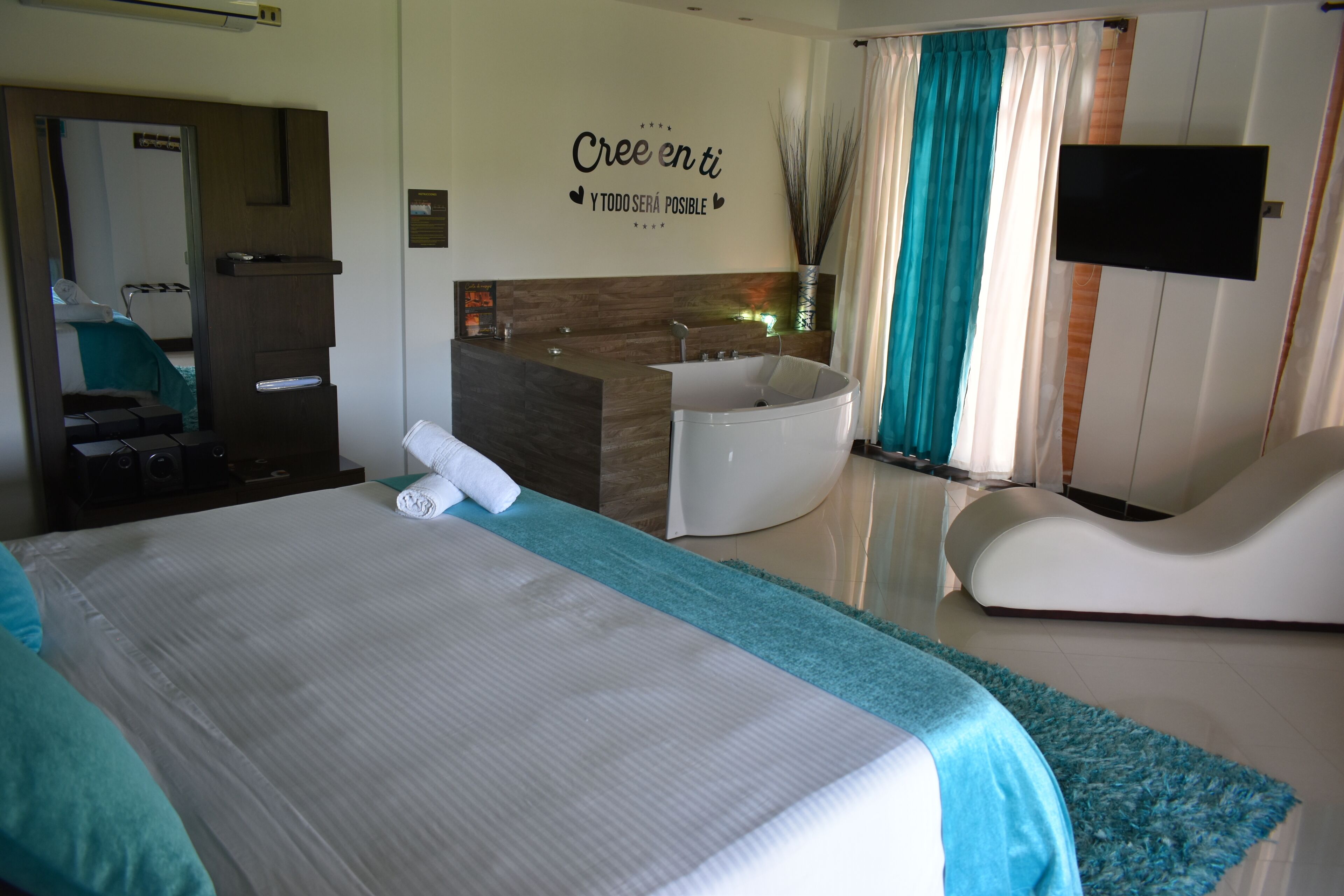 Quarto de hotel com uma cama grande, banheiro com banheira, toucador e televisão de tela plana.