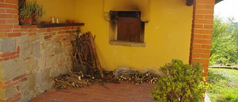 Un patio de ladrillo con una pared amarilla, una ventana pequeña y una maceta.