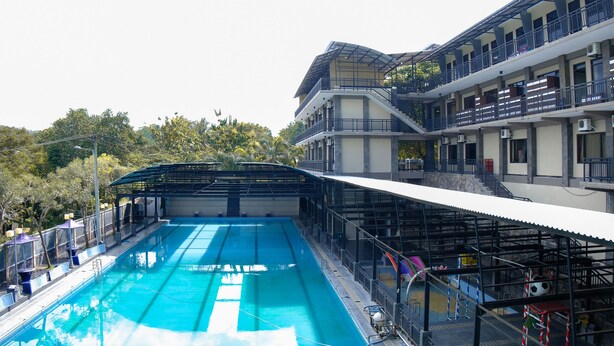A swimming pool with a covered area and a multi-story building with balconies.