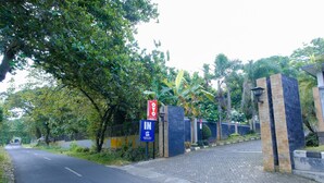 A road leading to a gated entrance with a sign indicating 'IN GREEN HILL'.