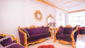 A room with two purple sofas and a gold-framed mirror. - Capital O 854 Ub Caisar Hotel (Banda Aceh)
