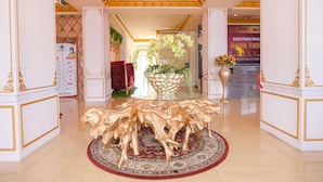 A luxurious lobby with a central glass table surrounded by golden lion sculptures, a red patterned rug, and a large potted plant. - Capital O 854 Ub Caisar Hotel (Banda Aceh)