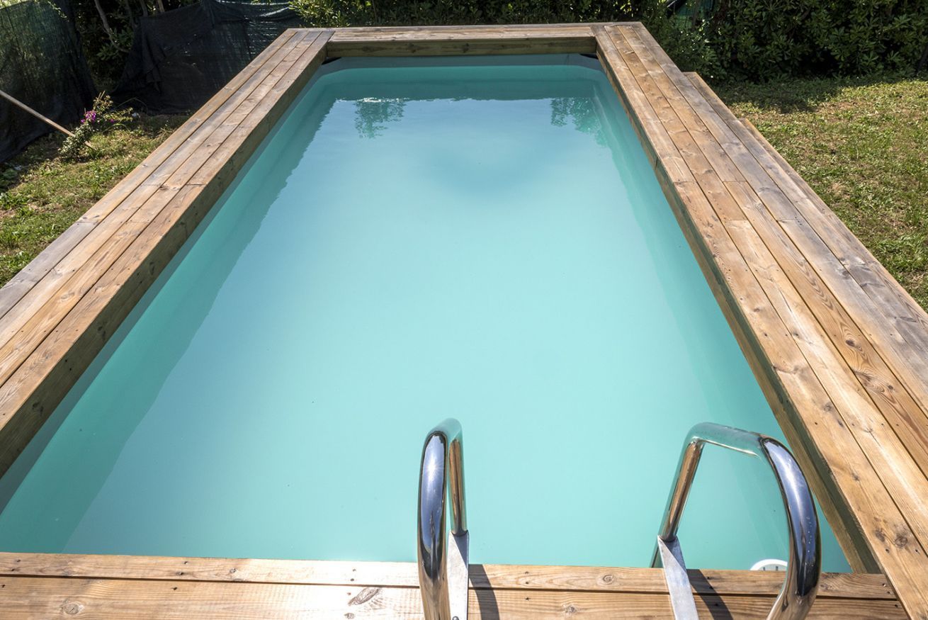 A rectangular wooden pool with clear water, surrounded by a wooden deck.