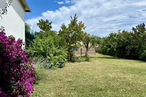 A well-maintained garden with a variety of plants and trees, a clear sky, and a building in the background. - N084 - Numana, villa with garden and pool (Numana)
