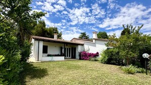 A house with a white exterior, a tiled roof, and a small garden with various plants. - N084 - Numana, villa with garden and pool (Numana)