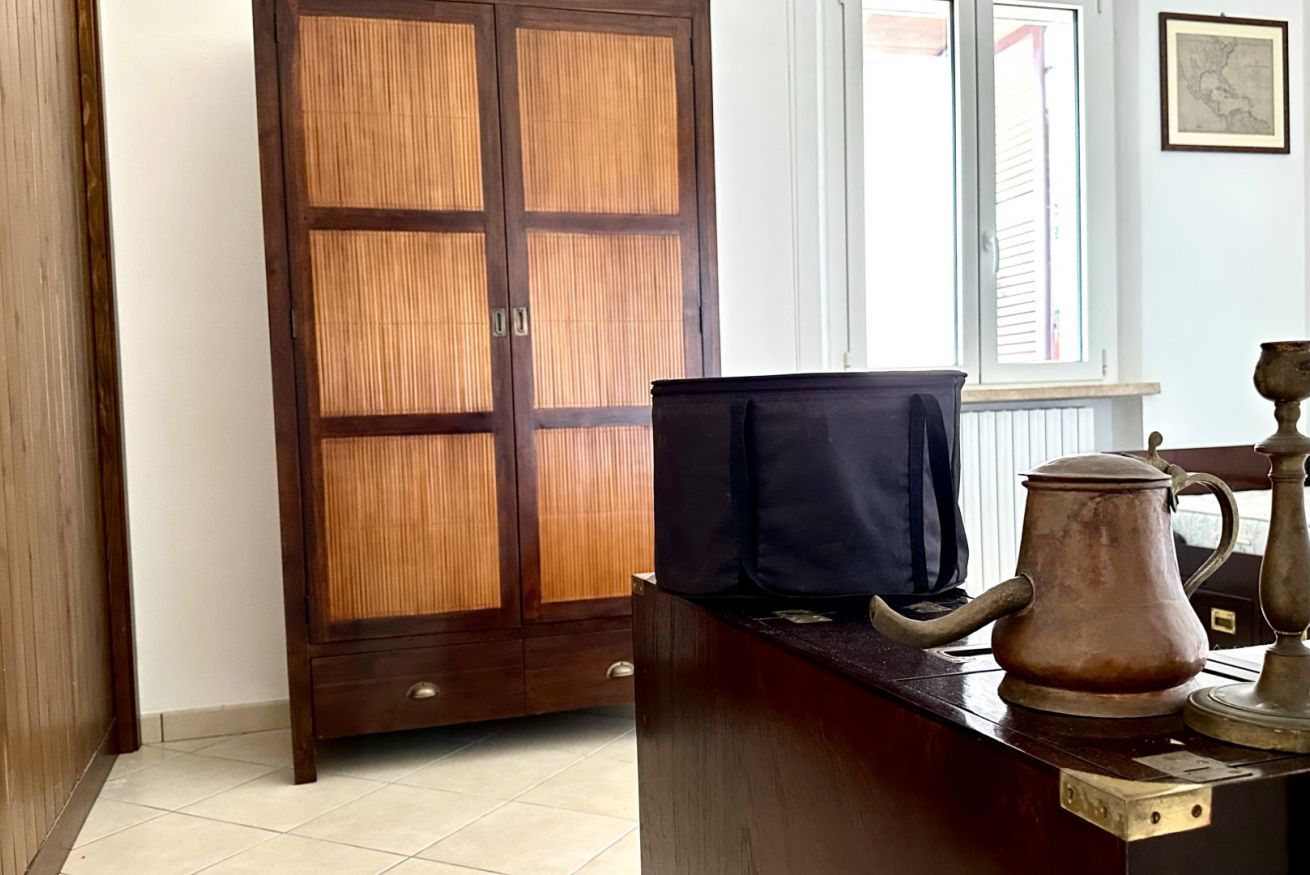 Una habitación con un armario de madera, un escritorio con hervidor y una ventana con persianas.