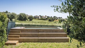 A swimming pool with wooden steps leading up to it, surrounded by grass and trees. - N084 - Numana, villa with garden and pool (Numana)