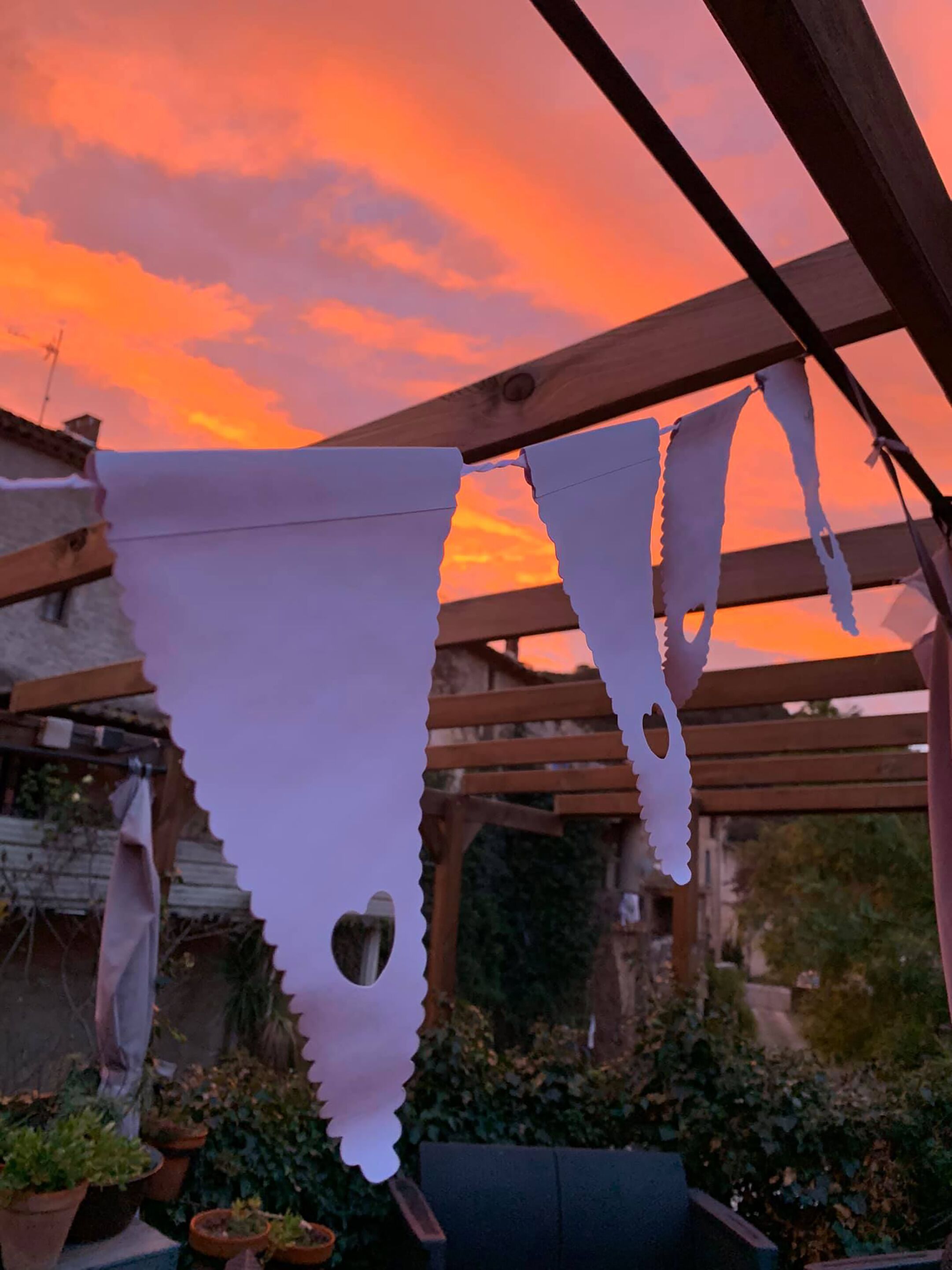 Una pérgola de madera con adornos blancos triangulares colgando.