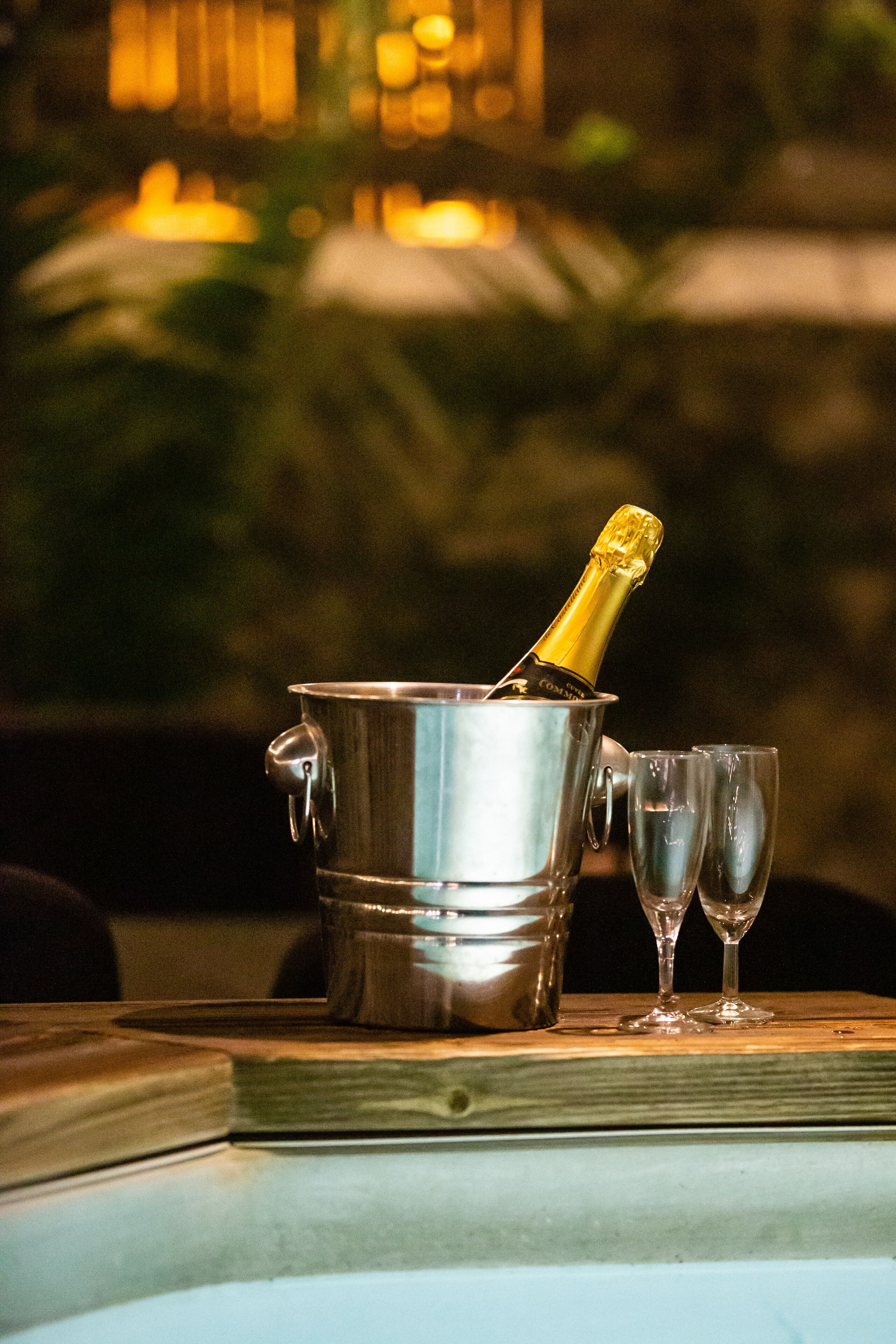 A metallic champagne bucket with a bottle of champagne on a table.
