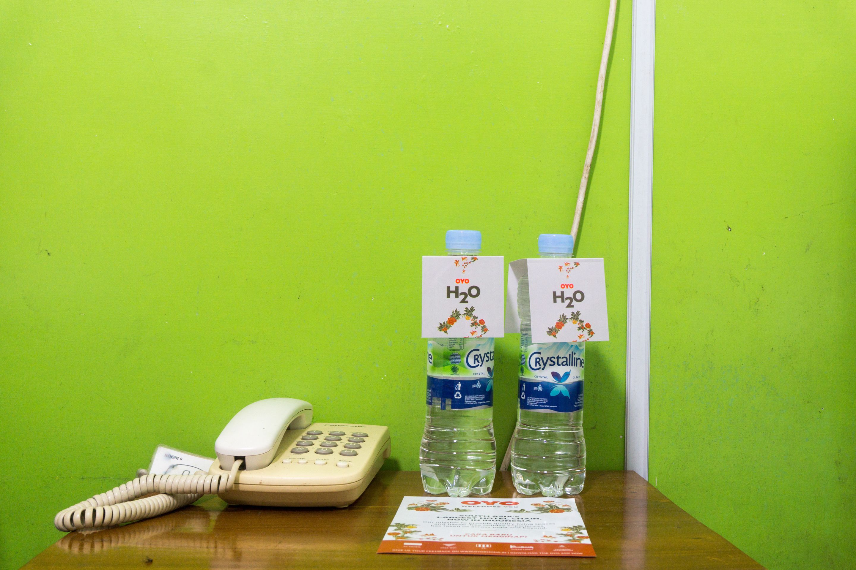 A desk with a telephone, two water bottles labeled "H2O Crystal", and a brochure.