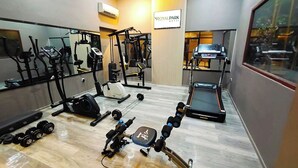 A gym with various exercise equipment, including treadmills, weight machines, and dumbbells. - Royal Park Hotel (Samarinda)