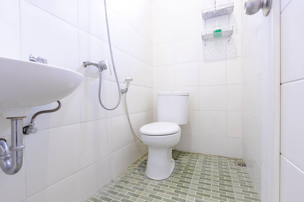 A small bathroom with a white sink, toilet, and shower.