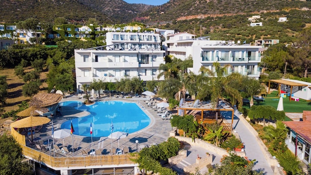 Um hotel moderno com uma piscina grande, várias varandas e vegetação exuberante.