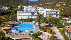 A modern hotel with a large swimming pool, multiple balconies, and lush greenery. - Resol Hotel (Mylopotamos)