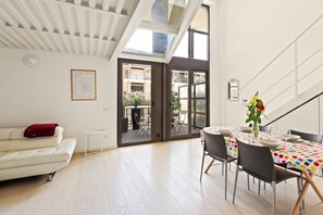 A modern living space with a sofa, dining table, chairs, and a staircase. - GuestHost - NEW! Exclusive Loft with balcony & garden! (Milano)