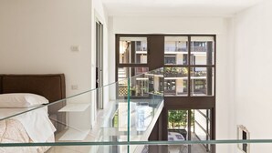 A modern bedroom with a glass balcony overlooking a residential area. - GuestHost - NEW! Exclusive Loft with balcony & garden! (Milano)