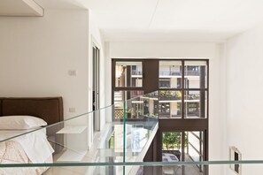 A modern bedroom with a glass balcony overlooking a residential area. - GuestHost - NEW! Exclusive Loft with balcony & garden! (Milano)