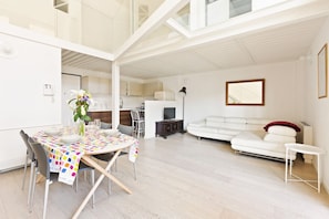A modern living space with a dining area, kitchen, and seating area. - GuestHost - NEW! Exclusive Loft with balcony & garden! (Milano)