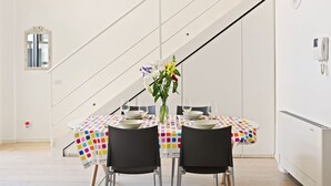 A dining area with a table set for two, a vase with flowers, and a staircase in the background. - GuestHost - NEW! Exclusive Loft with balcony & garden! (Milano)