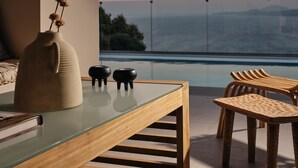 Un comedor moderno con una mesa de vidrio, sillas de madera y un jarrón con flores secas.