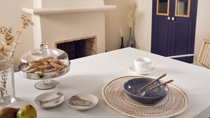 Una mesa de comedor con un bol de vidrio transparente, una taza blanca y palillos.
