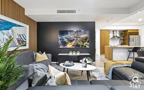Un salon moderne avec un canapé gris, une table basse et un tableau représentant un paysage urbain accroché au mur.