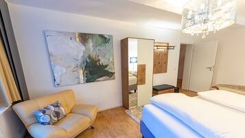 Una habitación de hotel moderna con cama, sofá, un cuadro abstracto grande y un espejo.