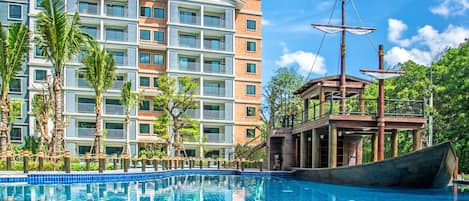 Un hotel con piscina, un bote de madera y palmeras.