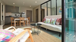 Un appartement moderne comprenant un coin repas, une kitchenette et un canapé agrémenté de coussins colorés.