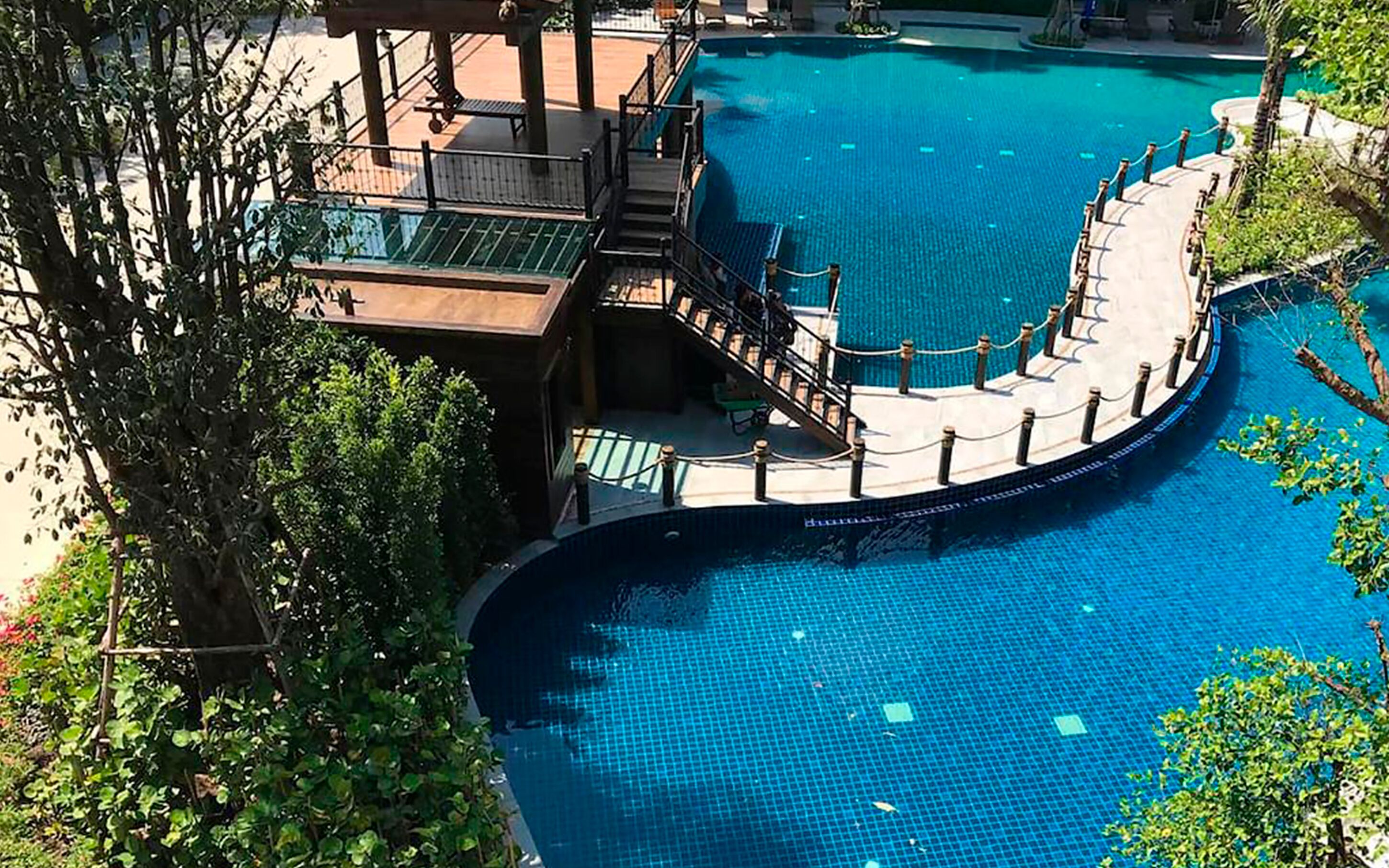 Una gran piscina al aire libre con diseño curvo, rodeada por una terraza con escalones que dan al agua.