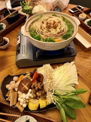 A hot pot meal with various vegetables and meats, a portable electric stove, and a plate with assorted mushrooms and vegetables. - Statt de Vallee - Campsite (Kaohsiung)