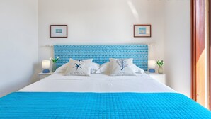 A neatly made bed with a blue quilt, white pillows, and a blue patterned headboard.