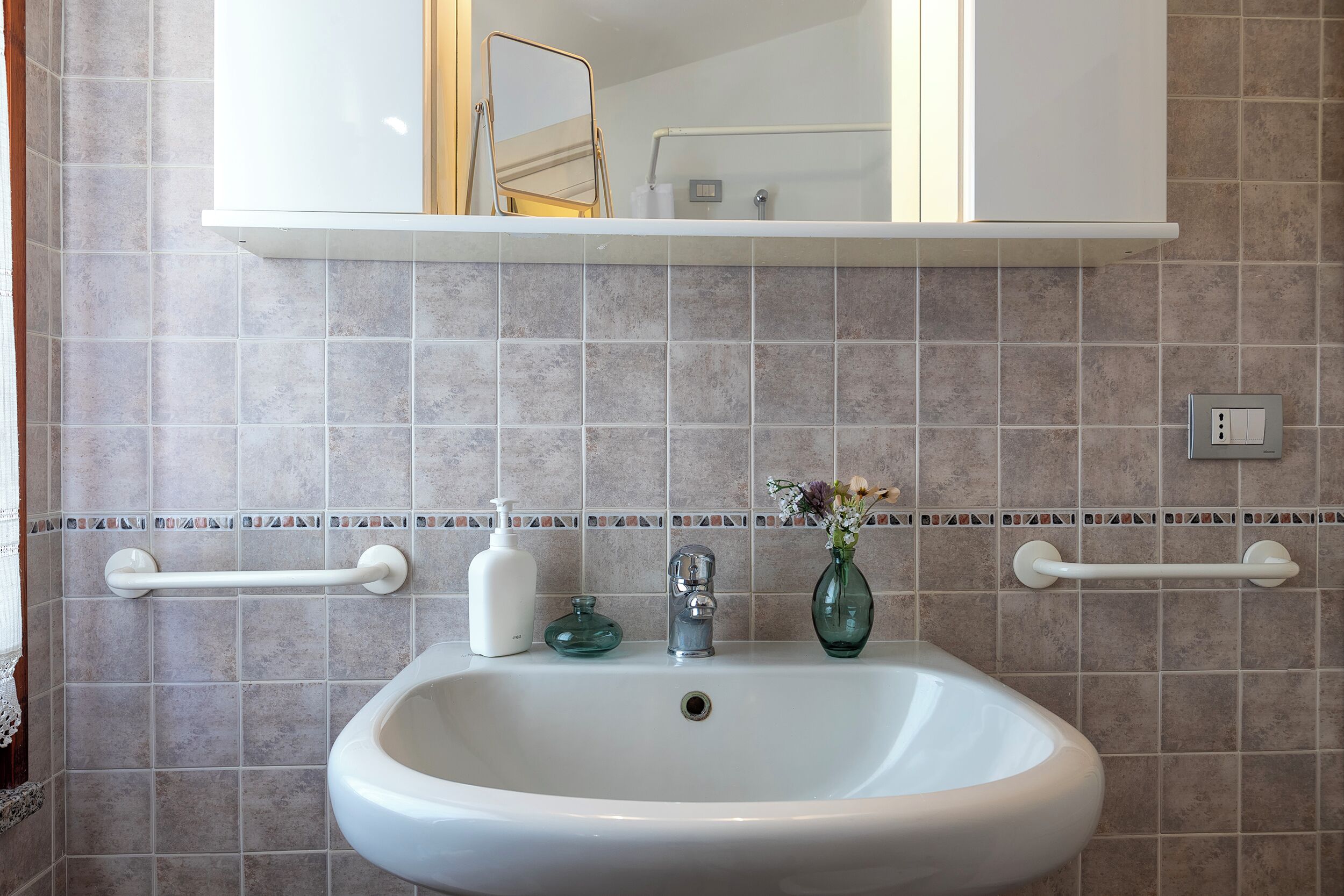 Une salle de bain avec un lavabo blanc, un miroir et un porte-serviettes.
