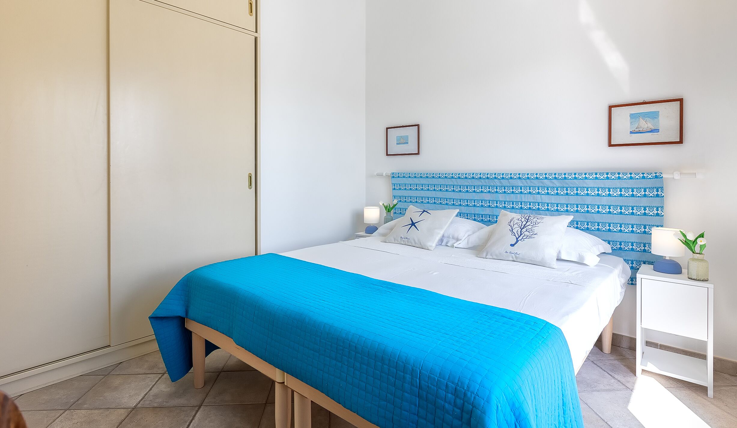 A bedroom with a bed, a nightstand, a wardrobe, and a headboard with a patterned design.