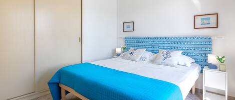 A bedroom with a bed, a nightstand, a wardrobe, and a headboard with a patterned design.