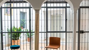 Ein Zimmer mit großem Fenster, blauem Stuhl, orangefarbenem Stuhl und einer Topfpflanze.