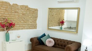 Ein Wohnzimmer mit braunem Sofa, einer weißen Anrichte, einem Glastisch und einem Spiegel an der Wand.