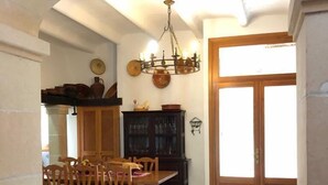 A dining area with a wooden table and chairs, a chandelier, and a cabinet with dishes.