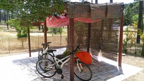 A bicycle parked under a woven structure with a patterned fabric canopy.