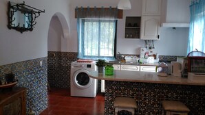 A compact kitchen with a washing machine, a sink, and a window with curtains.