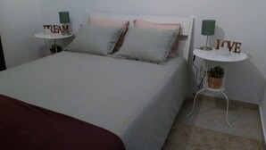 A neatly made bed with pillows, a small bedside table with a lamp, and a wall decoration.