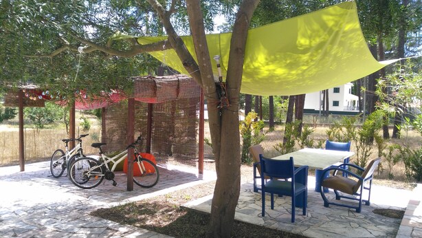 A patio area with a table and chairs, a bicycle, and a pergola with a yellow canopy.