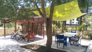 A patio area with a table and chairs, a bicycle, and a pergola with a yellow canopy. - Little Leisure House - Amazing Leisures, AL (Aroeira)