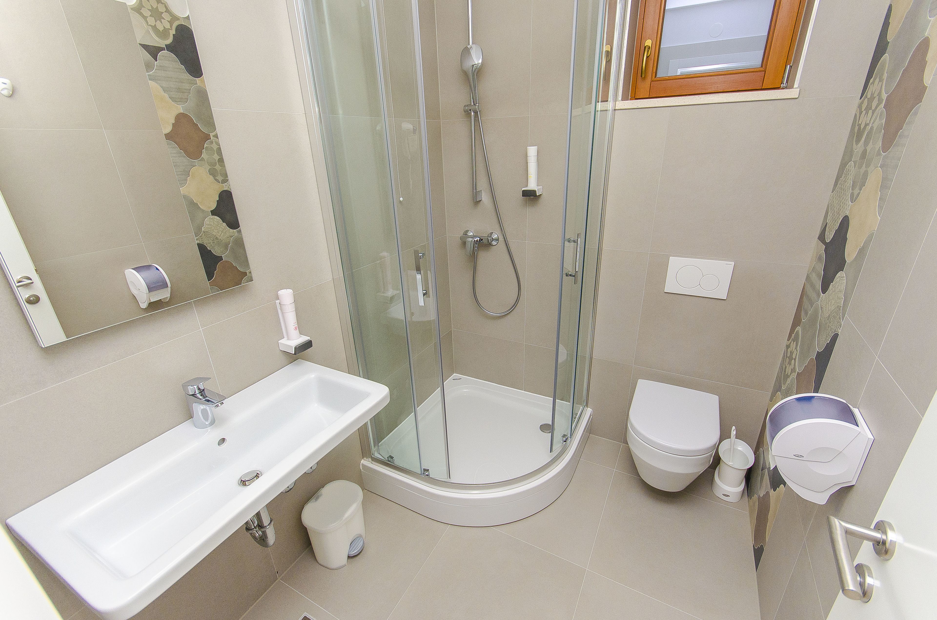 Un baño moderno con ducha de vidrio, lavamanos blanco y retrete.